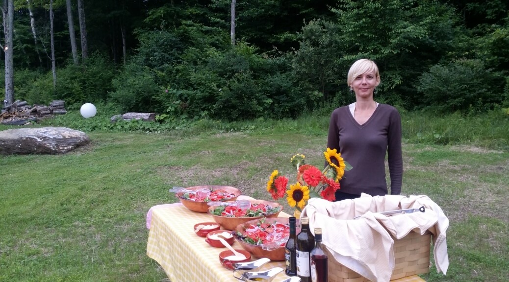 A woman standing next to a table with food on it.