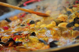 Seafood paella cooking with wooden spoon.