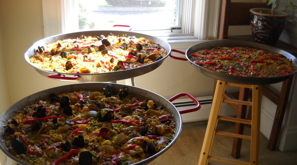 Three pans of pizza on a table in front of a window.