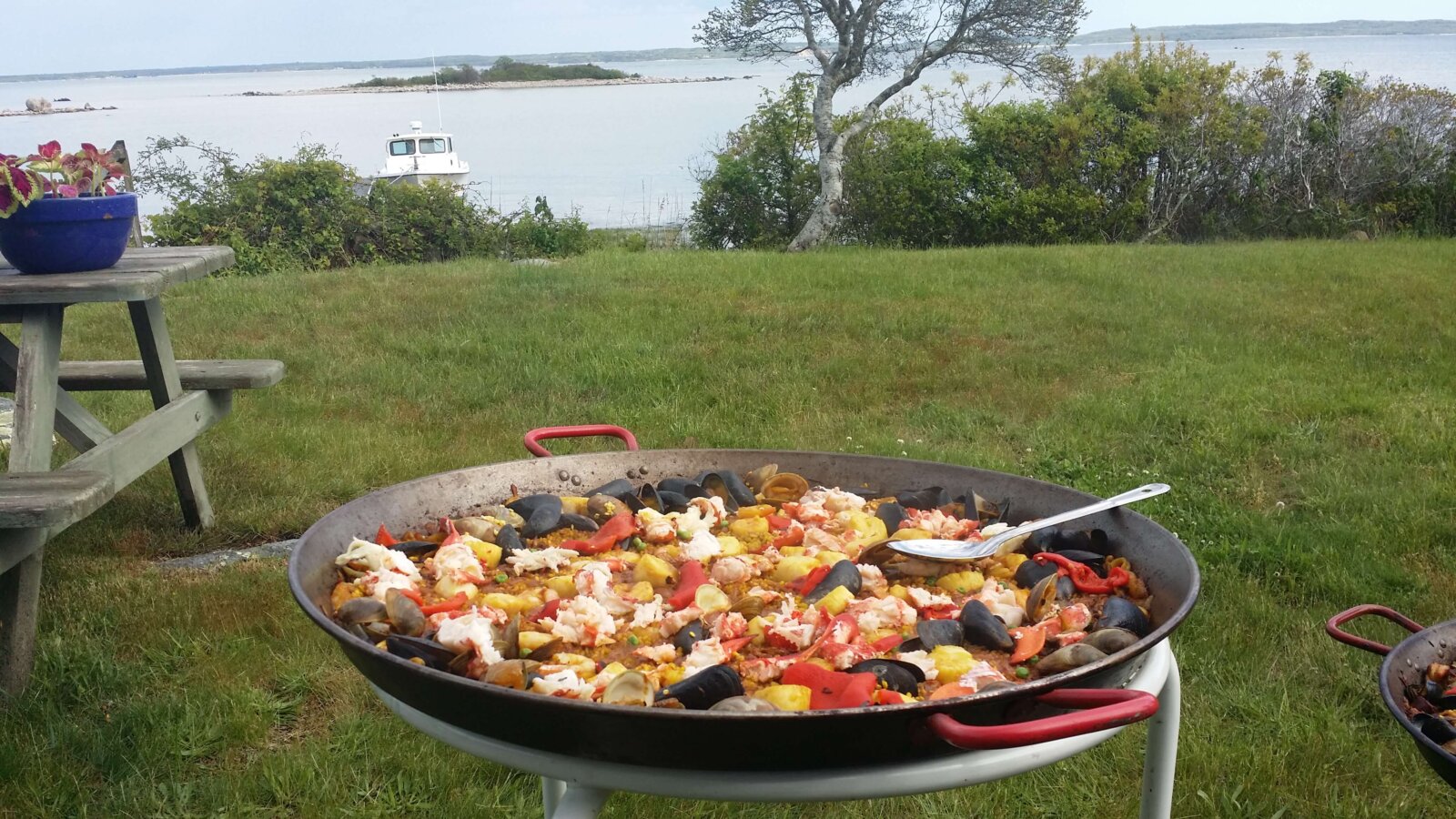 a huge pot of paella on a stand in a garden