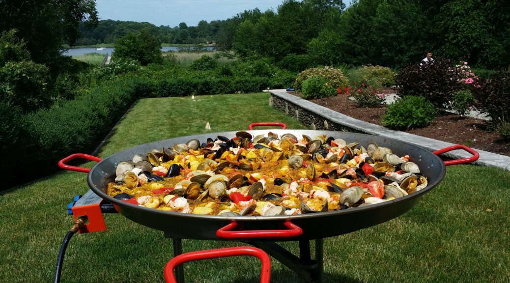 Paella in a big pan placed in a garden