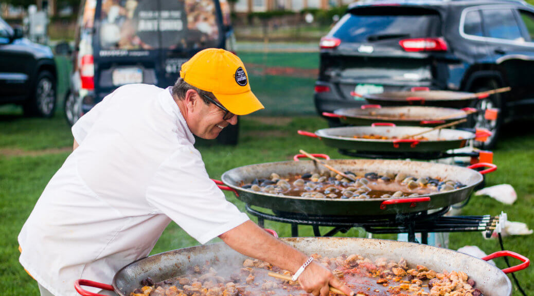 a man cooking paella in a huge pan