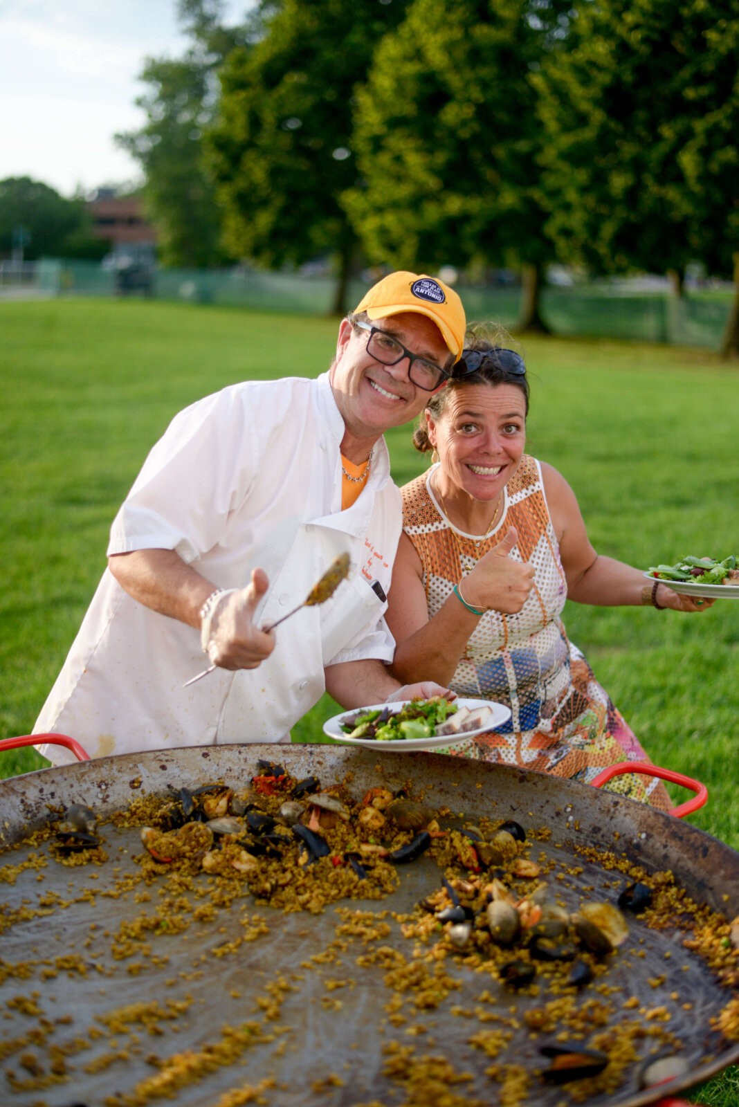 a man and woman with plates of Paella