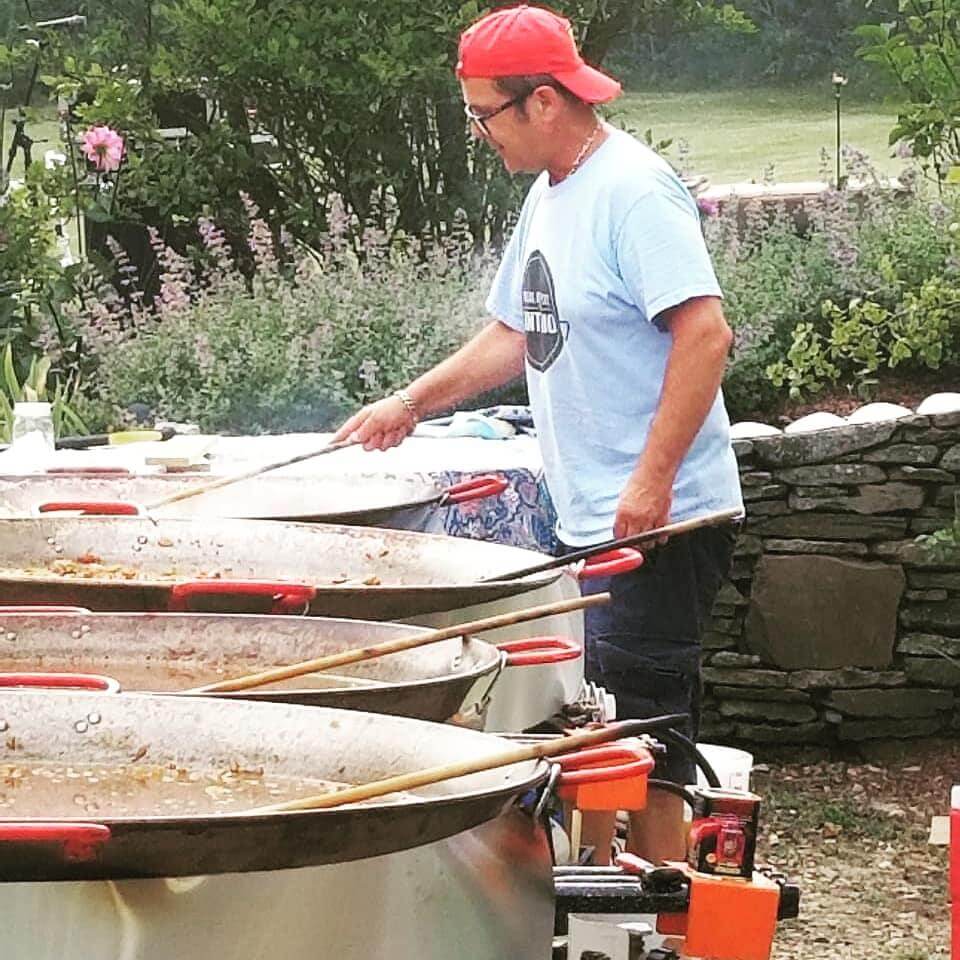 a man wearing a red cap is cooking Paella