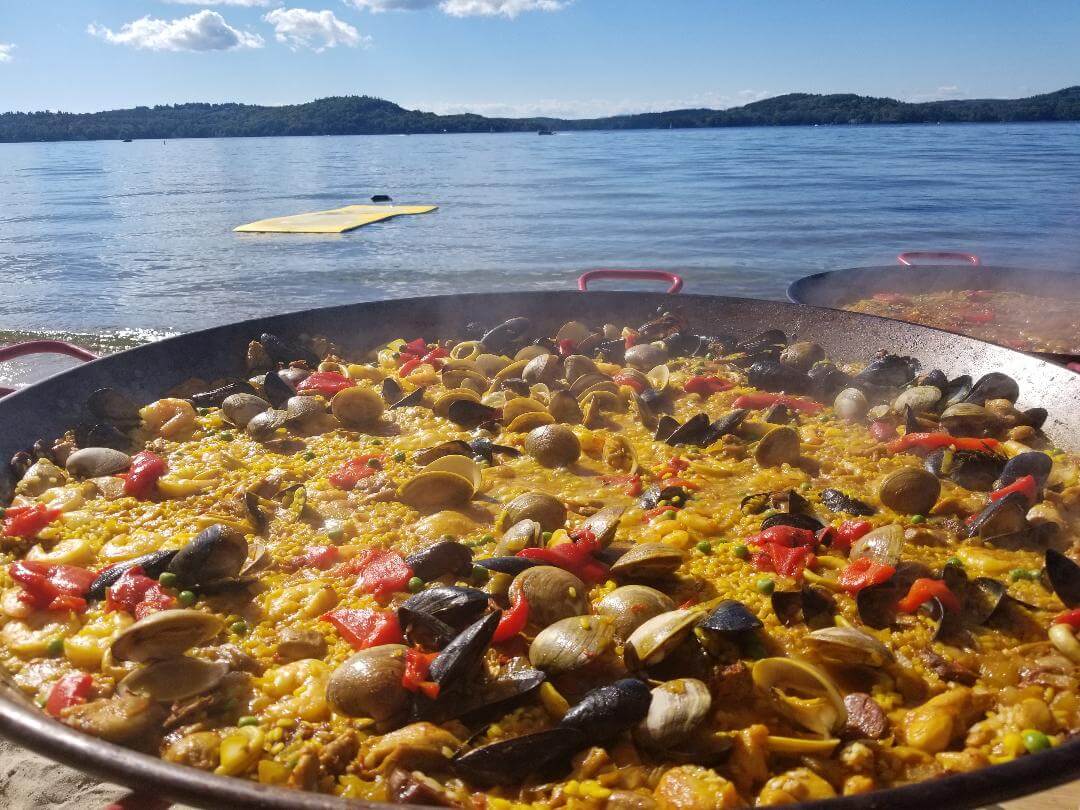 Closeup shot of the pan of paella and sea in the background