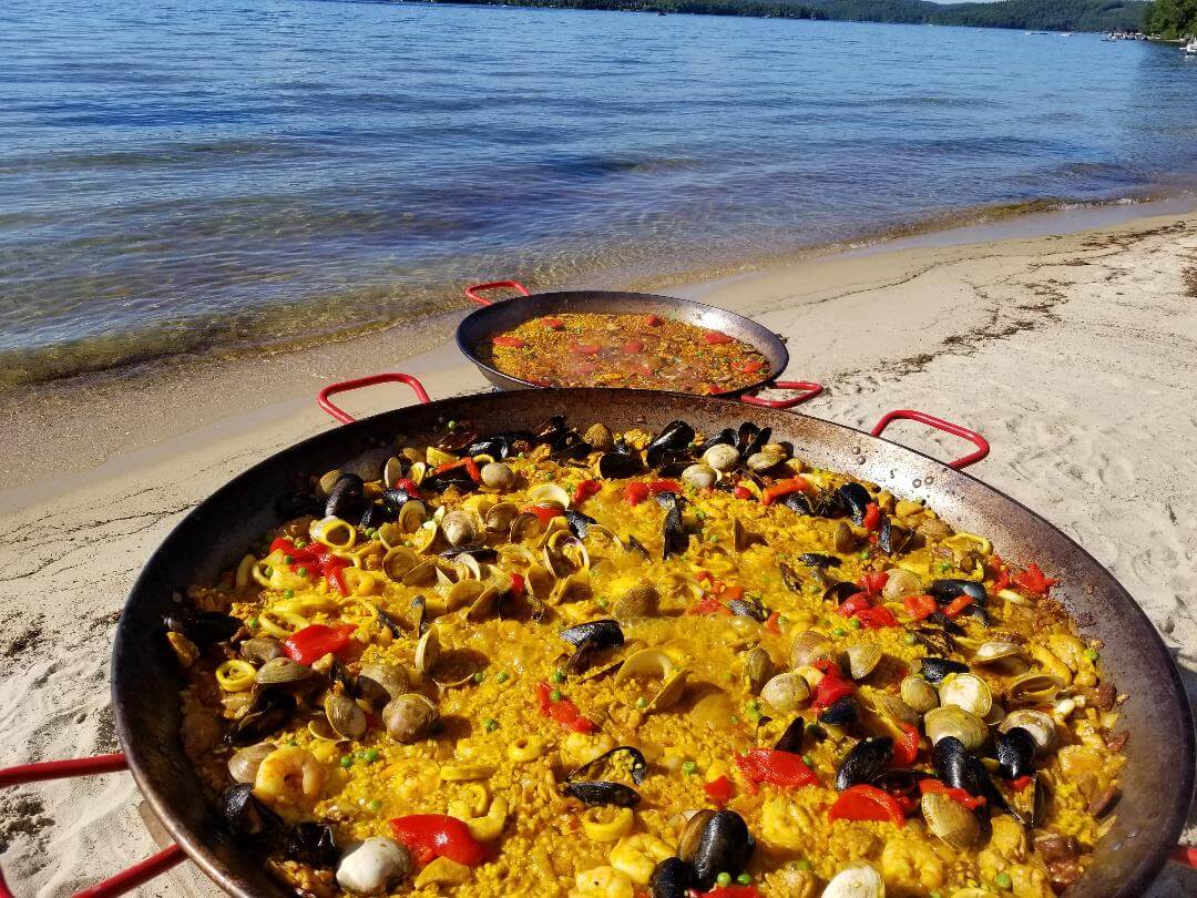 two pans of paella on the beach