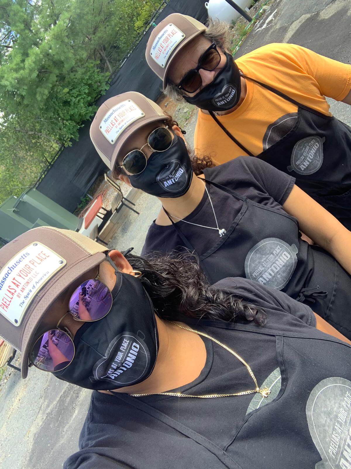 three people wearing caps, glasses, and masks