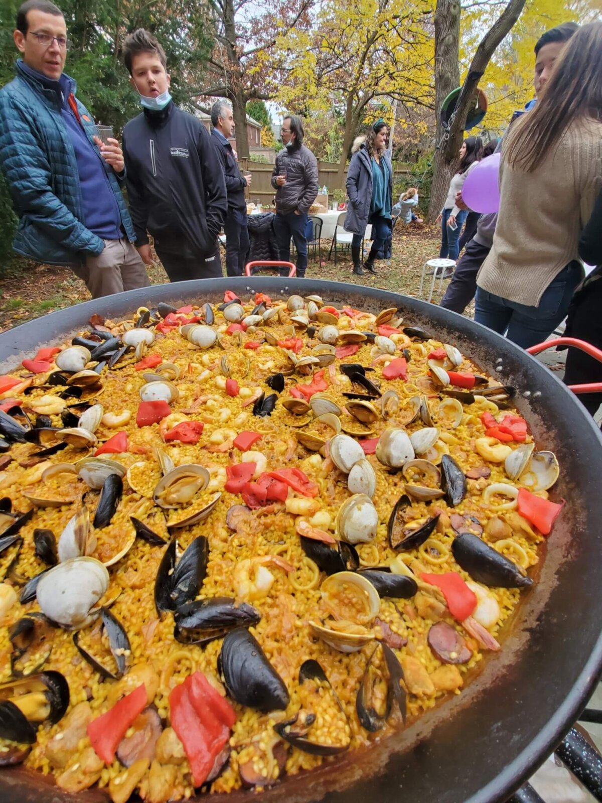 two people looking at a pan of Paella