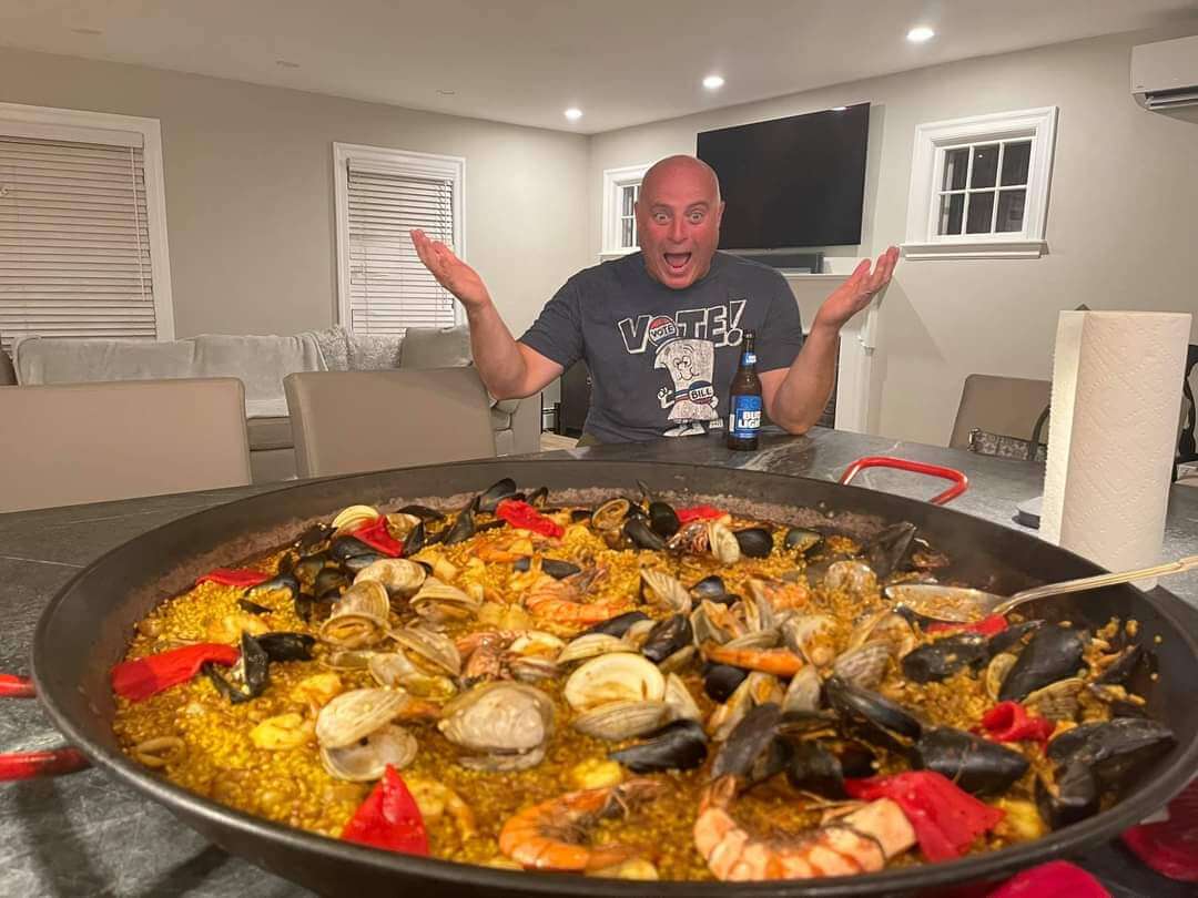 a man looking at a pan of Paella and surprised